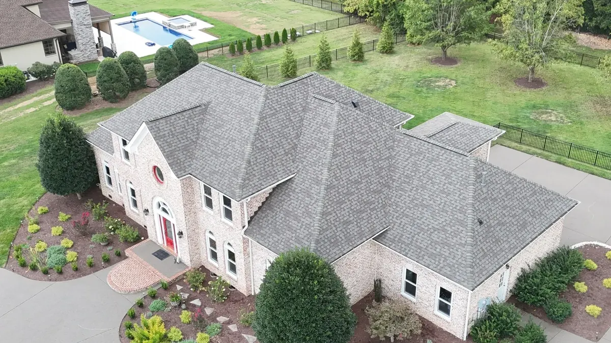 Aerial view of a new architectural shingle roof installed on a large brick home