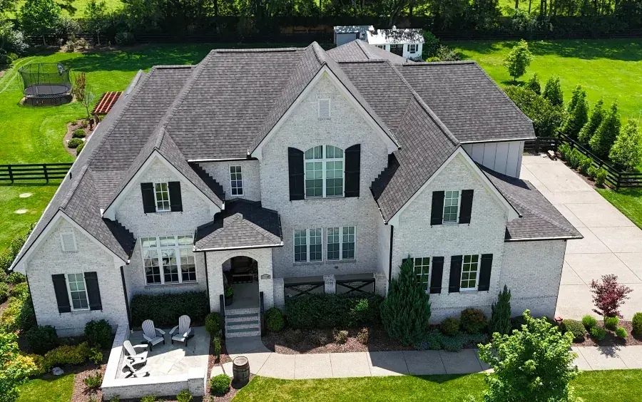 Aerial view of a new roof installed on a large white brick home