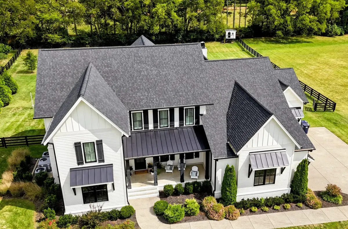 New roof installation on a white farmhouse-style home with dark architectural shingles